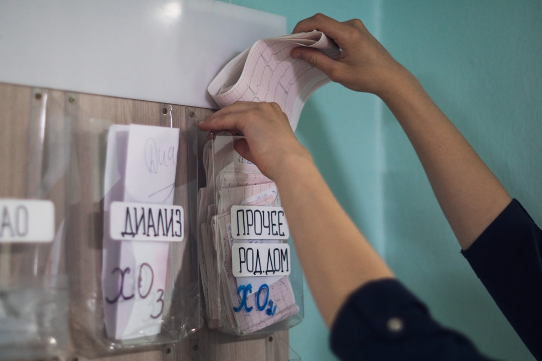 Hands place a paper into a medical chart holder.
