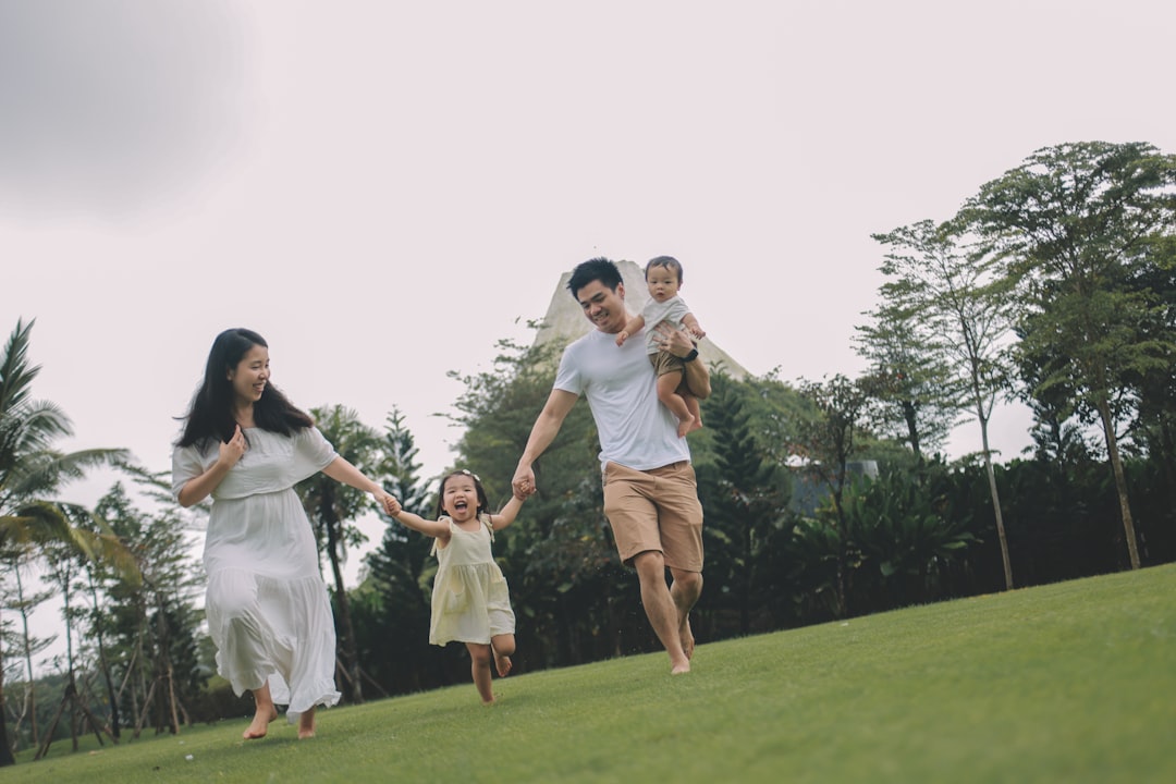 A family running happily on a grassy hill.