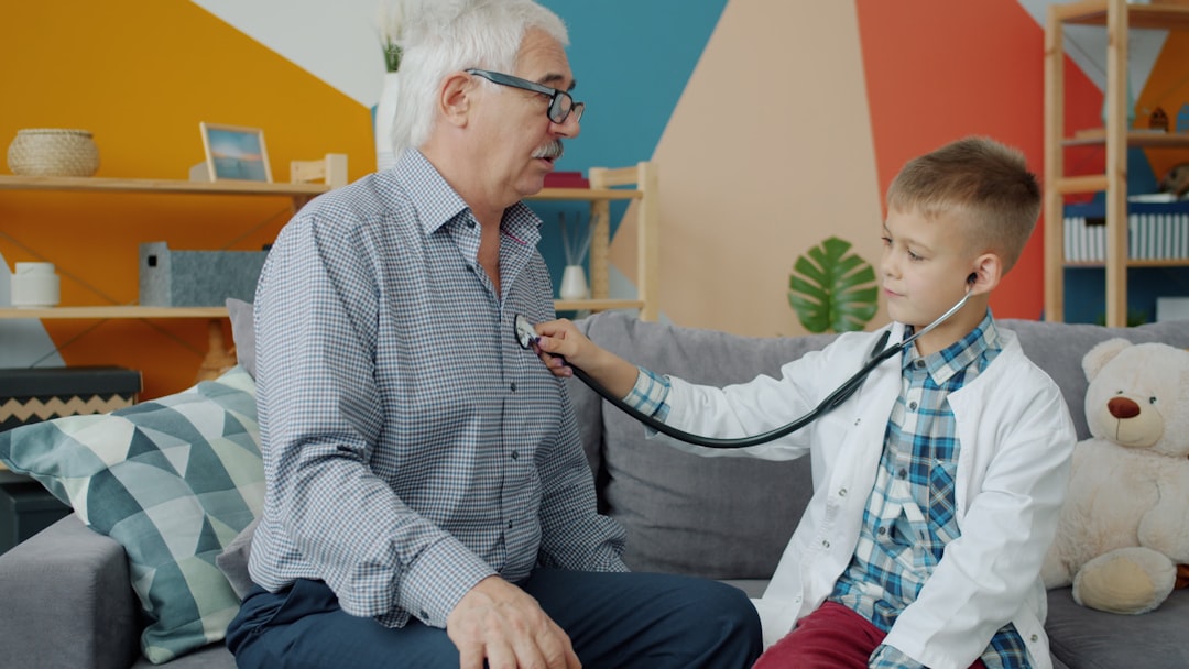 Boy in doctor's coat listens to grandfather's heart.