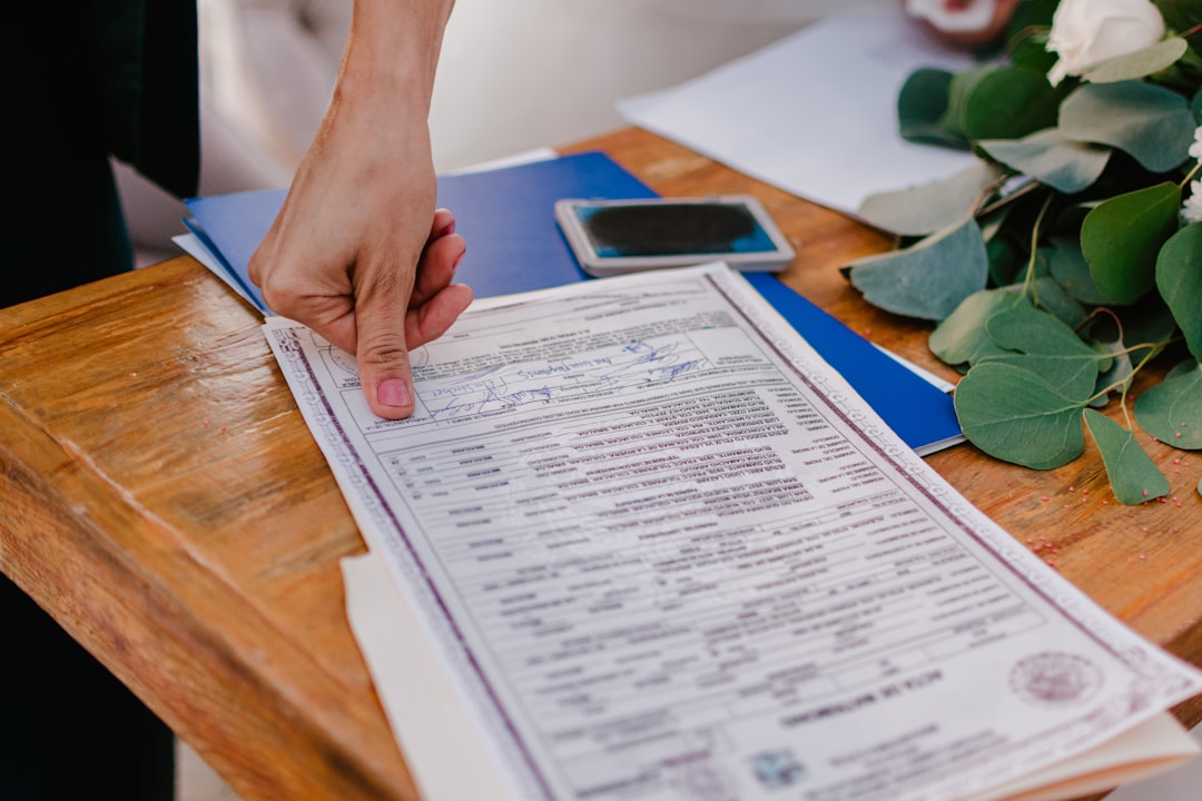 Person pointing at a marriage certificate on a wooden table.