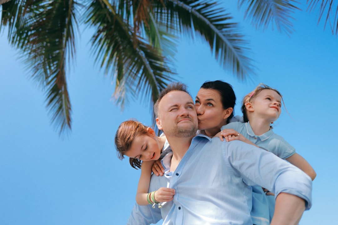 A family enjoys a sunny day under a palm tree.