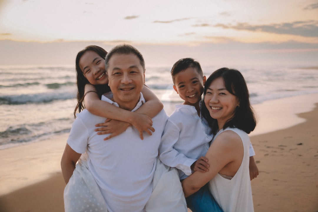 A happy family poses on a beach at sunset