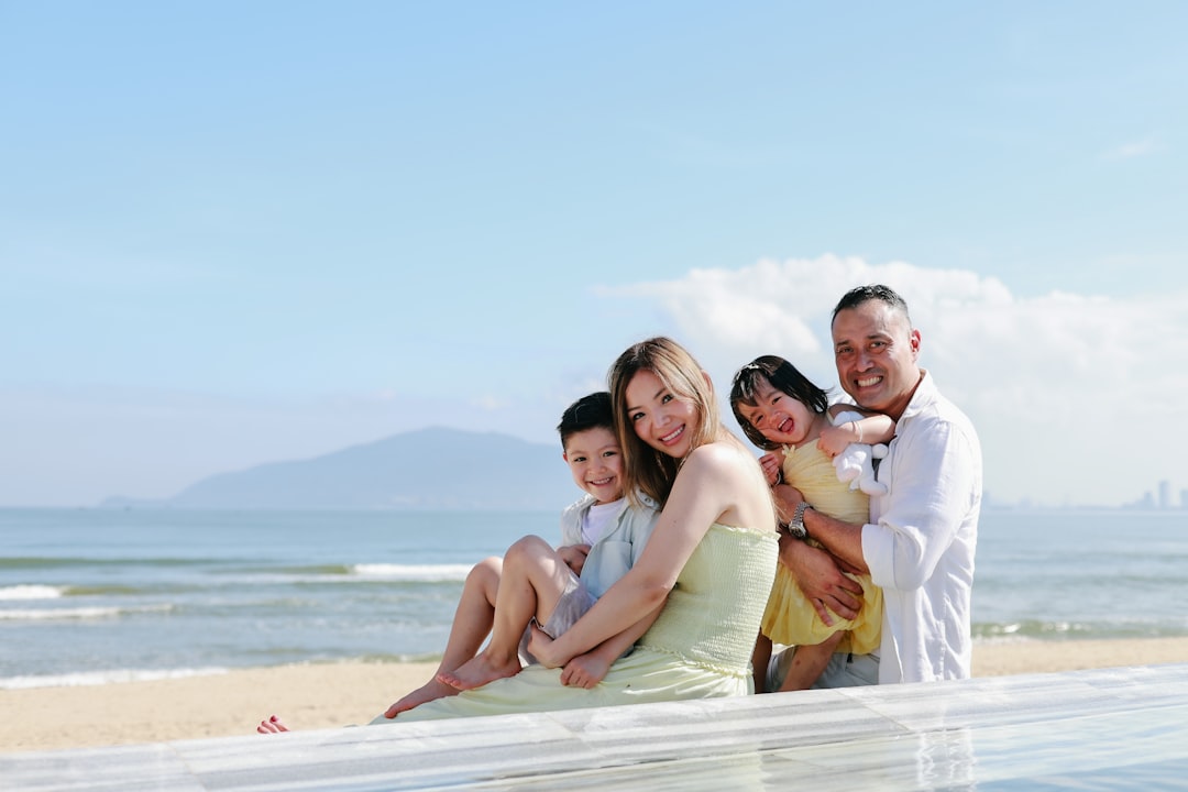Family posing by the ocean on a sunny day