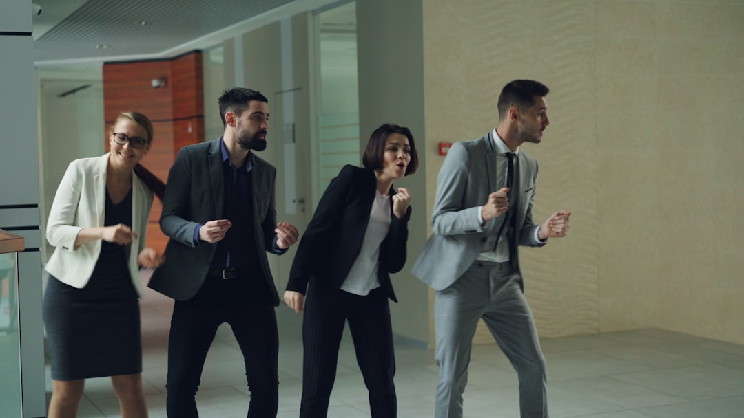 Four business people dancing in an office hallway.