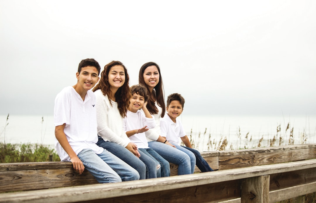 Family posing together on a wooden boardwalk by the ocean
