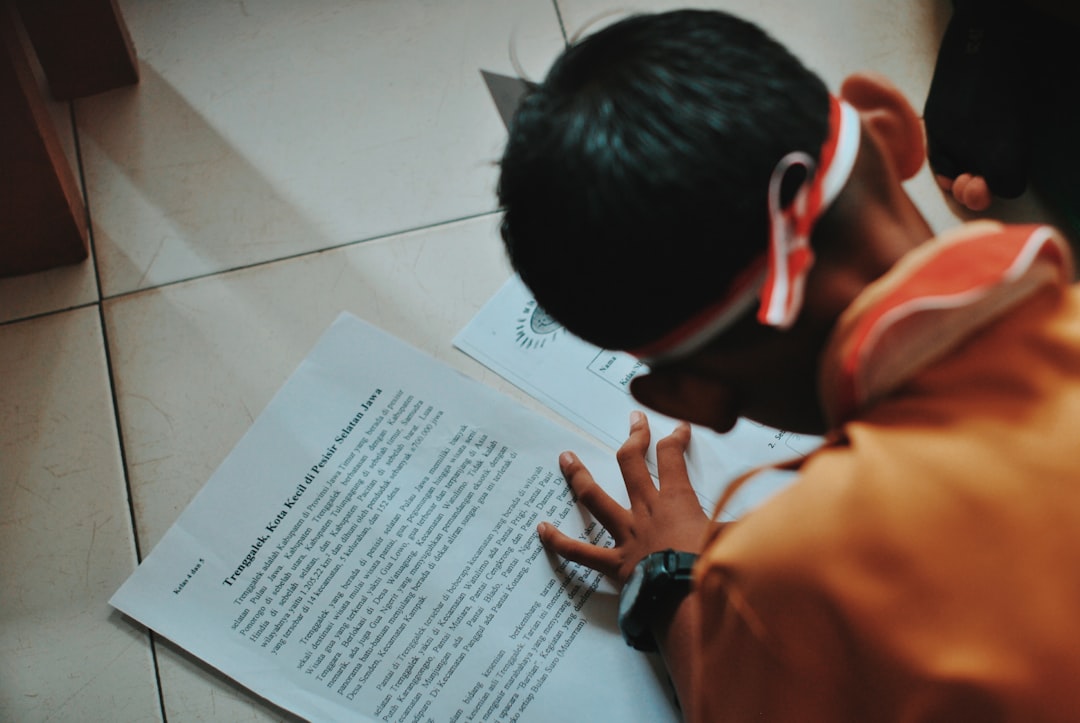 man in orange shirt writing on white paper