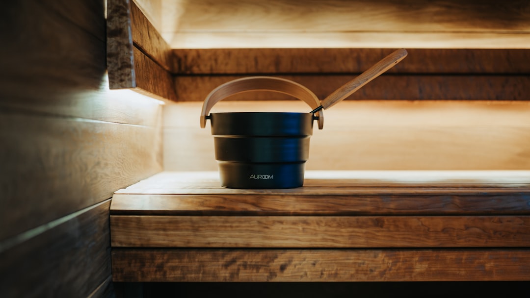 A black bucket and ladle on a wooden sauna bench